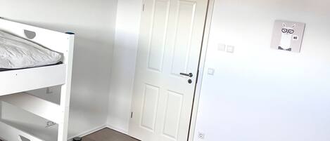 Una habitación con literas, una puerta blanca y una lámpara en el techo.