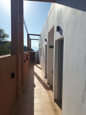 A corridor with tiled flooring, a fire extinguisher, and a sign reading "SALIDA" (exit).