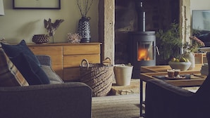 Una sala de estar acogedora con chimenea de piedra, un sofá, una mesa de centro y un televisor.