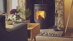 A cozy living room with a stone fireplace, a television, and a comfortable seating area. - Driftwood -  a pet friendly that sleeps 4 guests  in 2 bedrooms (Craster, Alnwick)