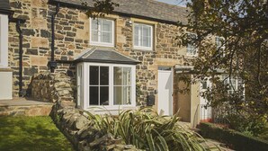 A stone building with a small porch and a window with shutters. - Driftwood -  a pet friendly that sleeps 4 guests  in 2 bedrooms (Craster, Alnwick)