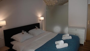 Et hotelværelse med seng, to sengeborde, en kommode og et spejl.