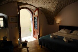 A bedroom with a bed, a wooden table with a bottle, a framed picture, and a door leading outside. - Tre Re Inn (Rijeka)