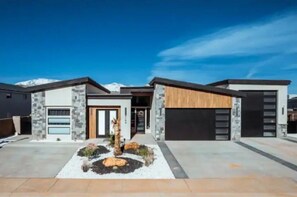 Stunning mountain views surround this elegant building, set amidst a beautifully landscaped area with a tree and rocks.