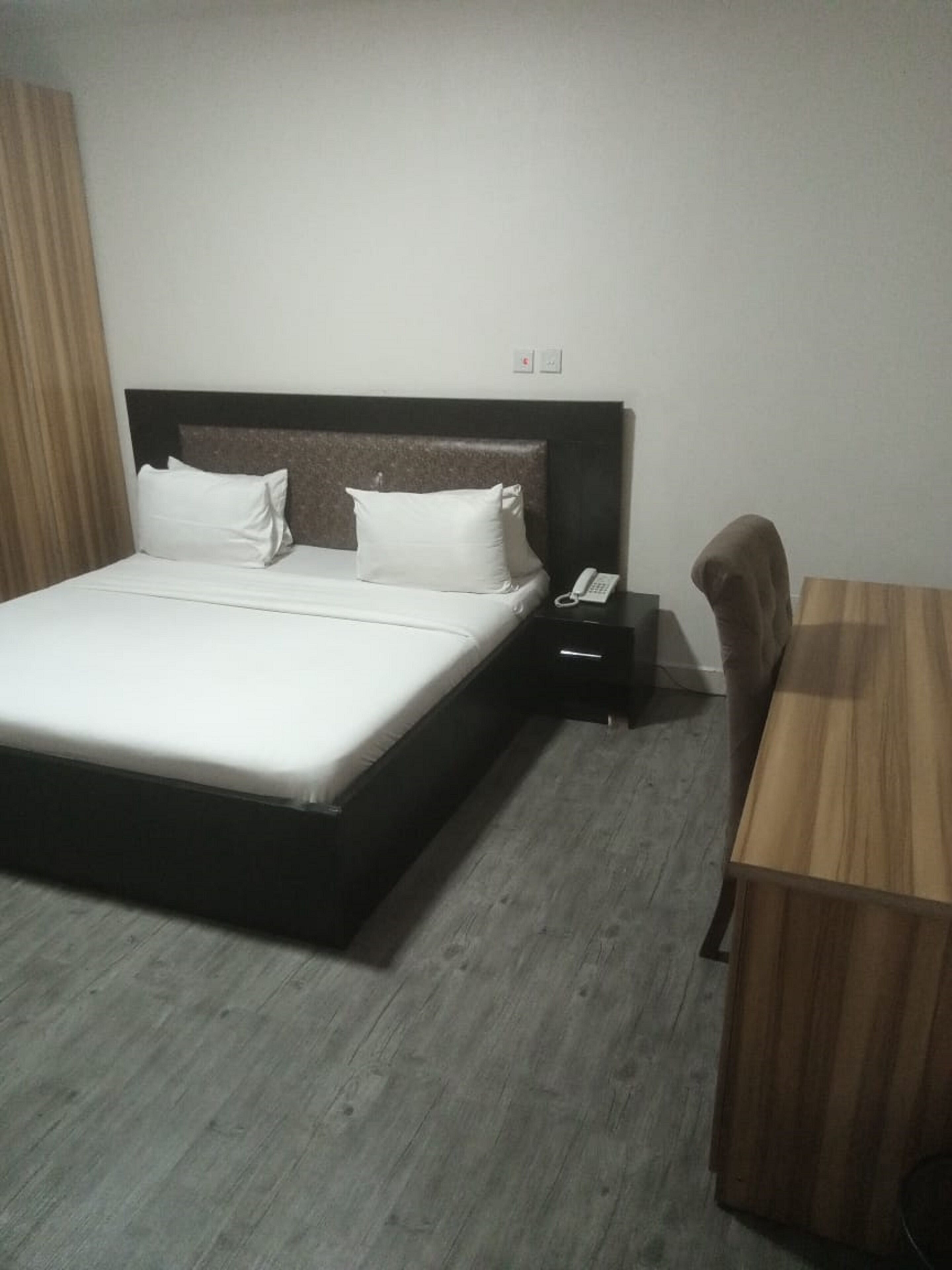 Una habitación de hotel con cama, mesita de noche y escritorio.