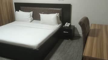 Una habitación de hotel con cama, mesita de noche y escritorio.