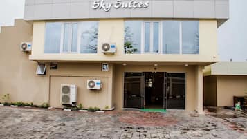 Un edificio con el letrero 'Sky Suites' sobre la entrada. Se observan unidades de aire acondicionado instaladas en las paredes exteriores.