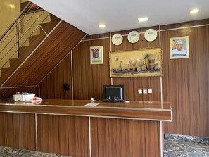 Un comptoir d’accueil avec un téléphone, un ordinateur et un tableau encadré accroché au mur.