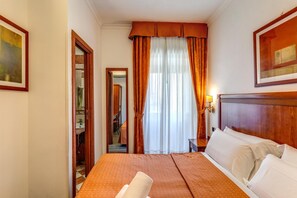 Ein Hotelzimmer mit einem großen Bett, einem Holzkopfende, einem Spiegel, einem Fenster mit Vorhängen und einem Gemälde an der Wand.