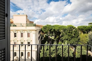 A balcony with a view of a classical building and lush trees. - Baltic Hotel (Rome)