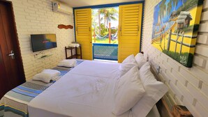 A hotel room with a bed, a TV, a window with yellow shutters, and a painting on the wall. - Manaí Pousada & Beach Club (Barra de Santo Antonio)