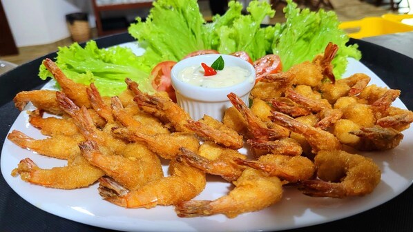 Un plato de camarones fritos con salsa para mojar y guarniciones.