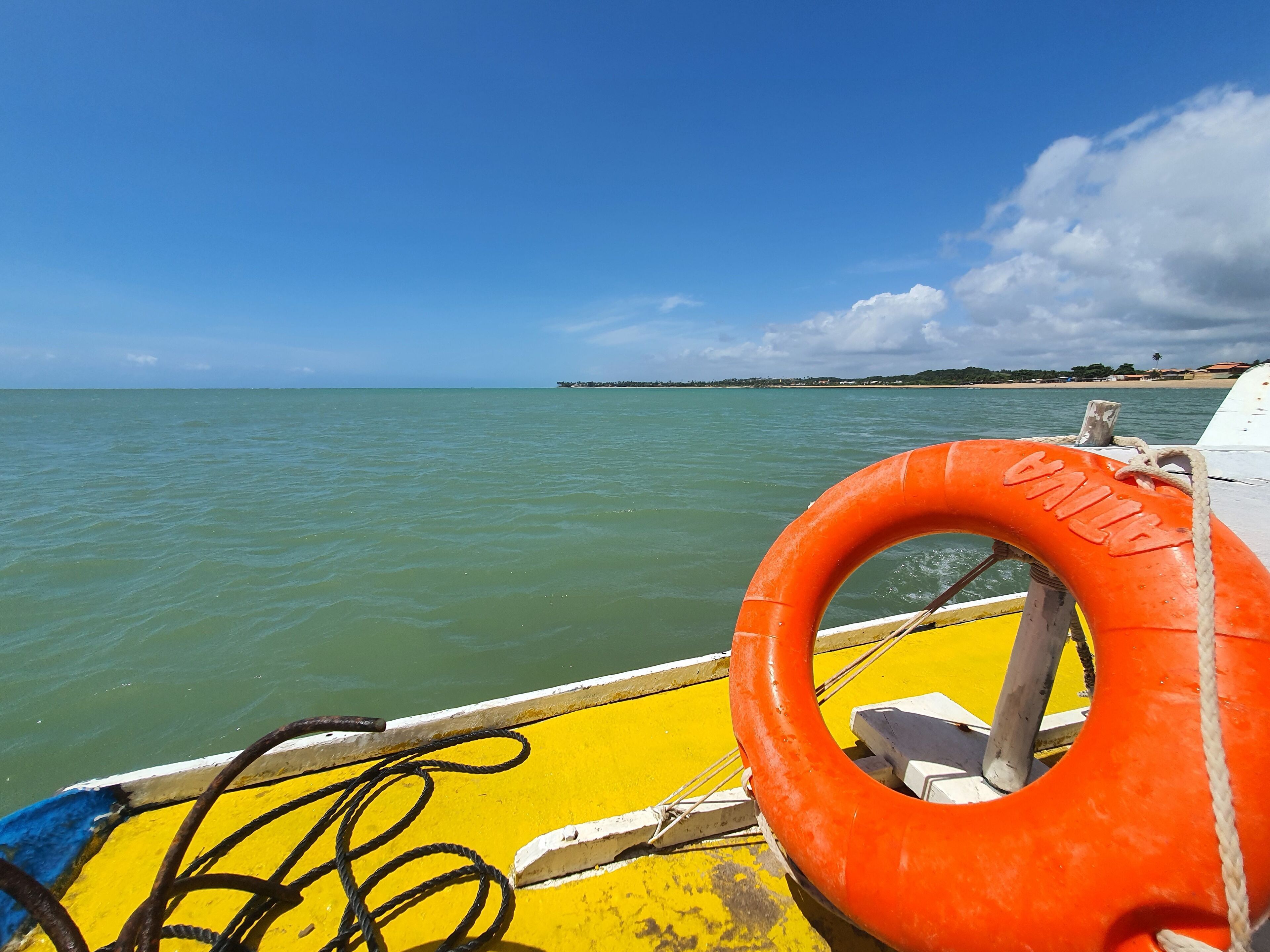 Un flotador en un bote con vista a aguas tranquilas y una costa distante.