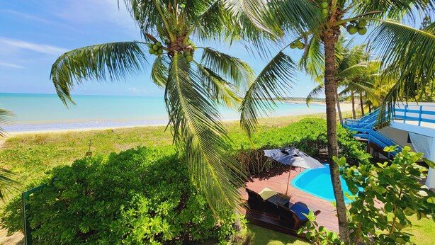 A tropical resort with a pool, lounge chairs, and a view of the beach. - Manaí Pousada & Beach Club (Barra de Santo Antonio)