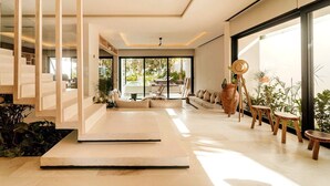 A modern interior with a staircase, a seating area, and a view of an outdoor pool. - Azumaya Beach House Tulum – Beachfront, Chef Included (Tulum)
