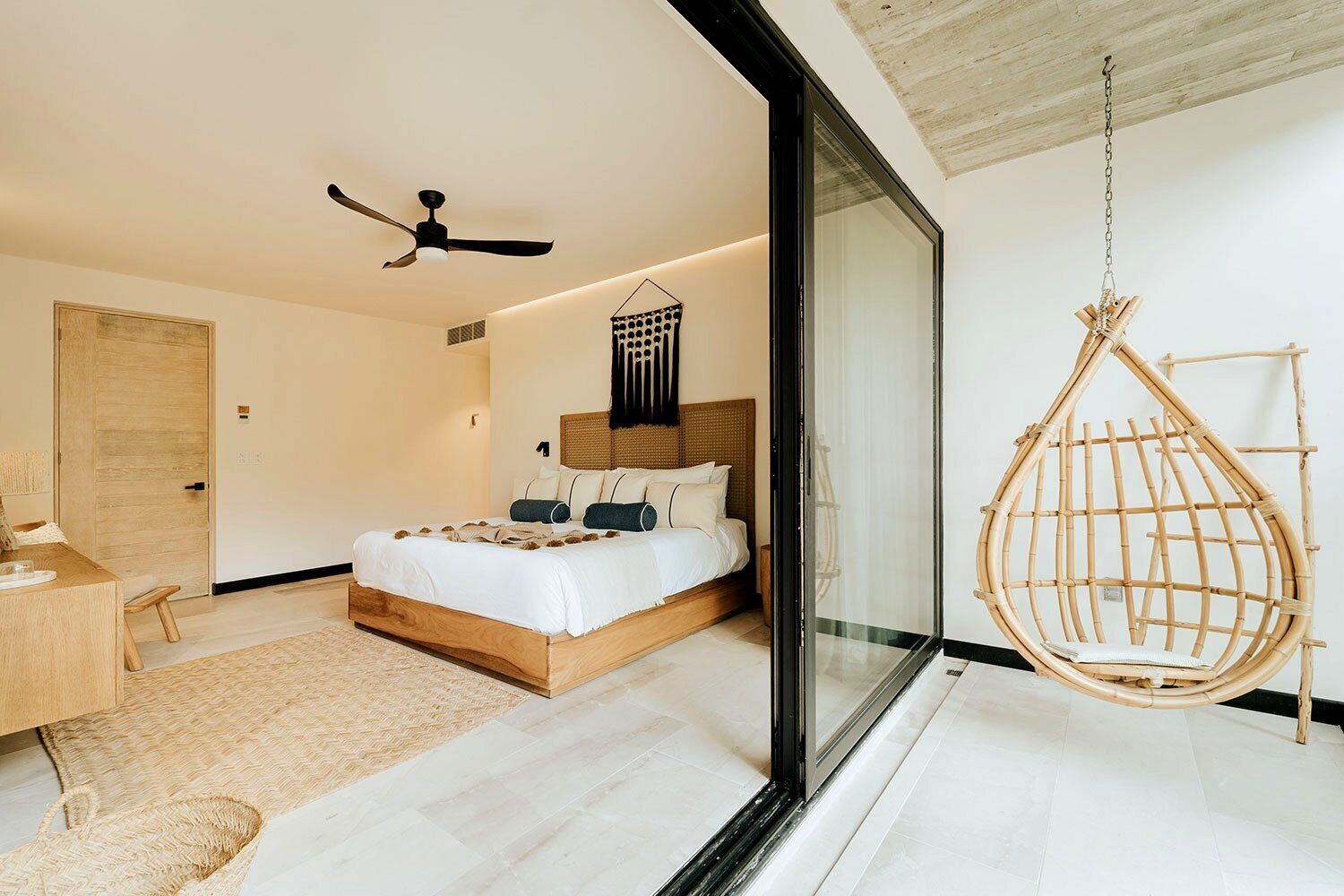 A modern bedroom with a bed, a hanging chair, and a desk.