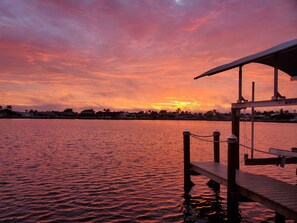 Une vue sur le coucher de soleil depuis un quai équipé d’un système de levage pour bateaux.