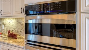 Forno a doppia leva in acciaio inox con pannello di controllo digitale, piano di lavoro in granito e pensile cucina.