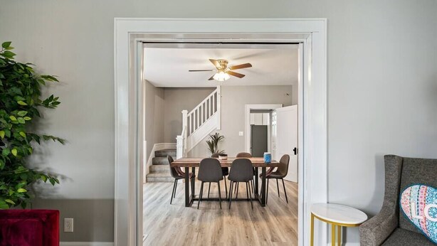 Ein Essbereich mit einem Holztisch und -stühlen, einem Deckenventilator und einer Treppe zu einem anderen Raum.