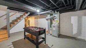 Ein Kellerraum mit Kicker, einer Treppe und einem Technikraum.