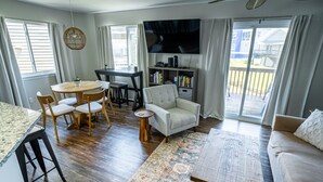 Un salon comprenant un coin repas, un canapé, un téléviseur et une bibliothèque.