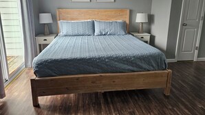 Une chambre à coucher avec un lit en bois, deux tables de chevet avec des lampes et deux tableaux encadrés accrochés au mur.
