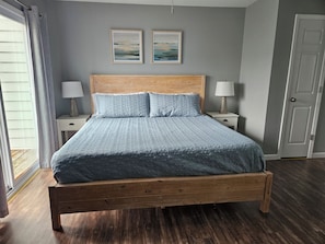 Een slaapkamer met een houten bed, twee nachtkastjes met lampen, en twee ingelijste foto's aan de muur.