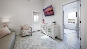Uma sala de estar com sofá, armário, ventilador de teto e uma janela ampla.