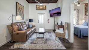 A living room with a leather sofa, a coffee table, a TV, and a patterned rug. - Ship Style Luxury Downtown, Boat Trailer Parking! (Cedar Key)