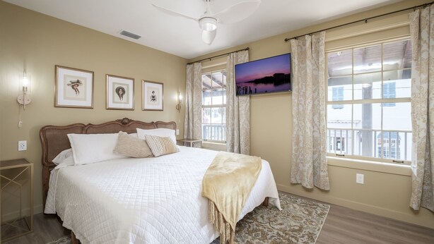 Un dormitorio con una cama grande, un ventilador de techo y un televisor en la pared.