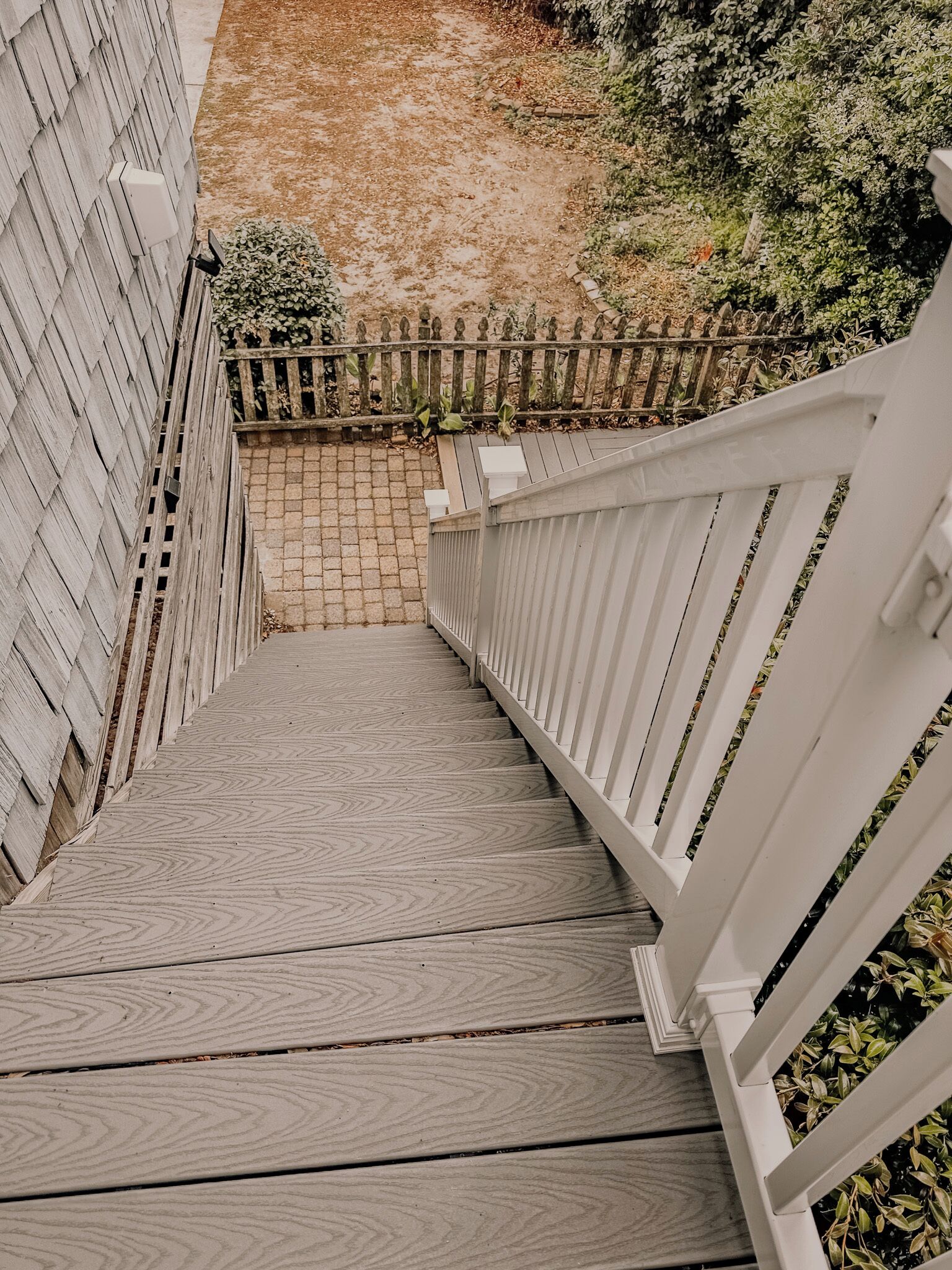 Una escalera de madera con barandillas blancas que lleva a una zona cubierta.