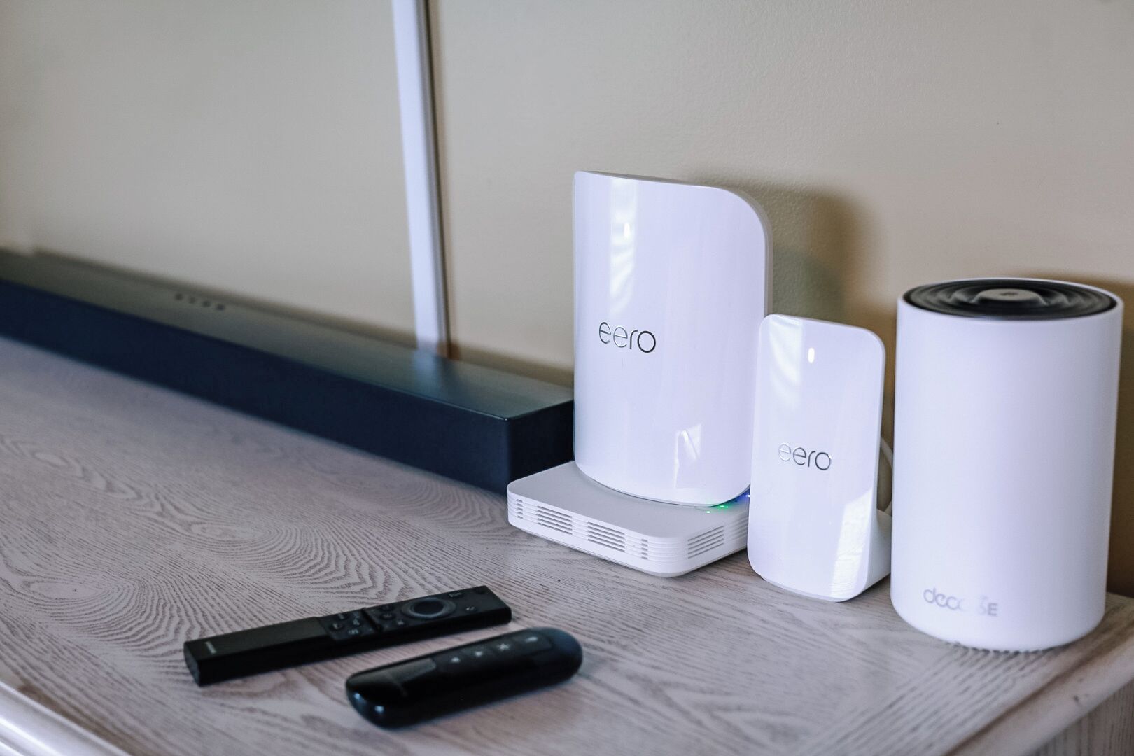 A set of white electronic devices on a wooden surface, including a remote control.