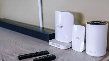 A set of white electronic devices on a wooden surface, including a remote control.