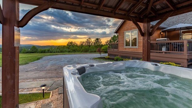 Ein Whirlpool unter einer Hollaube mit Blick auf ein Haus und einen bewölkten Himmel.