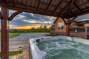 Un bain à remous sous une pergola en bois, avec vue sur une maison et un ciel nuageux.