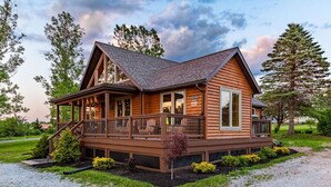 Eine Blockhütte mit Veranda, einer überdachten Terrasse und einem Schotterweg.