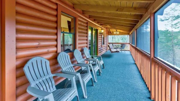 A covered porch with Adirondack chairs, wooden railings, and a view of the outdoors. - Cupid's Haven: Private Cabin Close To All (Sevierville)