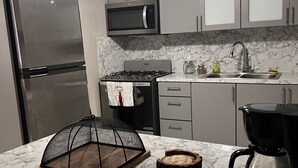 A modern kitchen with a stainless steel refrigerator, microwave, stove, and coffee maker. - Cozy Home w/ private parking- 10 min to beach (Arecibo)