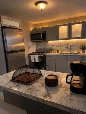 A modern kitchen with a stainless steel refrigerator, a microwave, a stove, and a coffee maker.