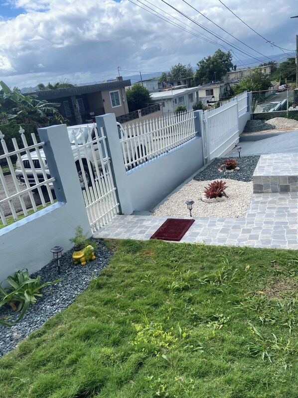 Un barrio residencial con una cerca blanca, un camino pavimentado y un césped.