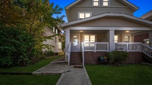 A two-story house with a front porch, a small front yard, and a wooden fence. - Stylish 5BRs Next to Expo Center & Near Stadium,2 Free parking (Columbus)