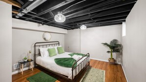 A modern bedroom with a metal bed frame, green bedding, a small bedside table, a potted plant, and exposed ceiling beams. - Stylish 5BRs Next to Expo Center & Near Stadium,2 Free parking (Columbus)