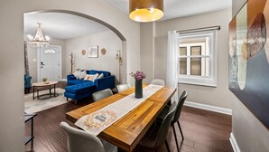 A dining area with a wooden table, chairs, a chandelier, and a blue sofa in the background. - Stylish 5BRs Next to Expo Center & Near Stadium,2 Free parking (Columbus)