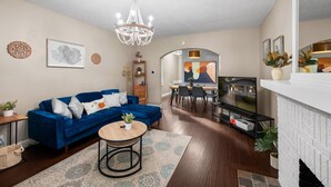 A living room with a blue sofa, a chandelier, a fireplace, and a dining area. - Stylish 5BRs Next to Expo Center & Near Stadium,2 Free parking (Columbus)
