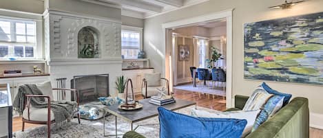 A spacious living room with a fireplace, green sofa, and a large painting.
