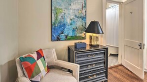 A room with a beige armchair, a black and gold side table, a colorful throw pillow, and a large abstract painting on the wall. - Bright Apartment 3 Mi to Downtown Birmingham! (Birmingham)
