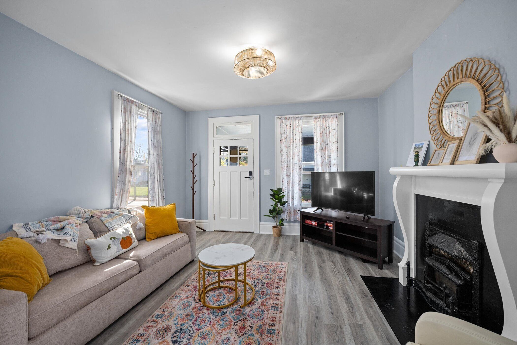 A living room with a sofa, TV, fireplace, and a decorative mirror.