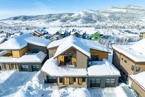 A modern ski resort with snow-covered buildings and a mountainous backdrop. - Wildhorse Summit | Private Gondola | Hot Tub, Pool, & Mountain Views (Steamboat Springs)