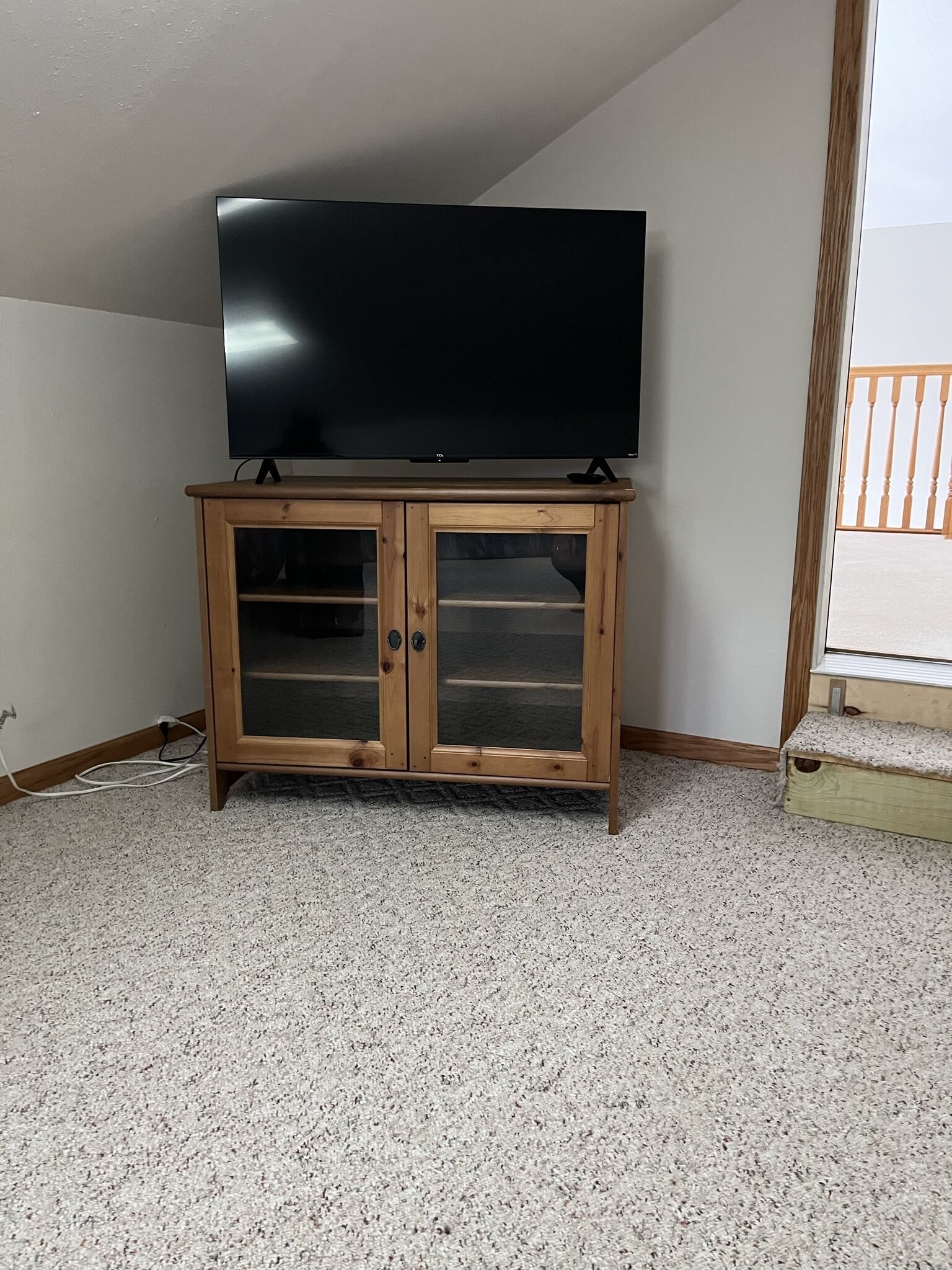 A wooden cabinet with glass doors and a flat-screen TV on top.