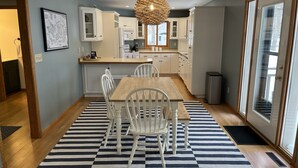 A modern kitchen with white cabinets, a wooden dining table, and a black and white striped rug.